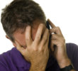 Man covering eyes in distress while on the phone